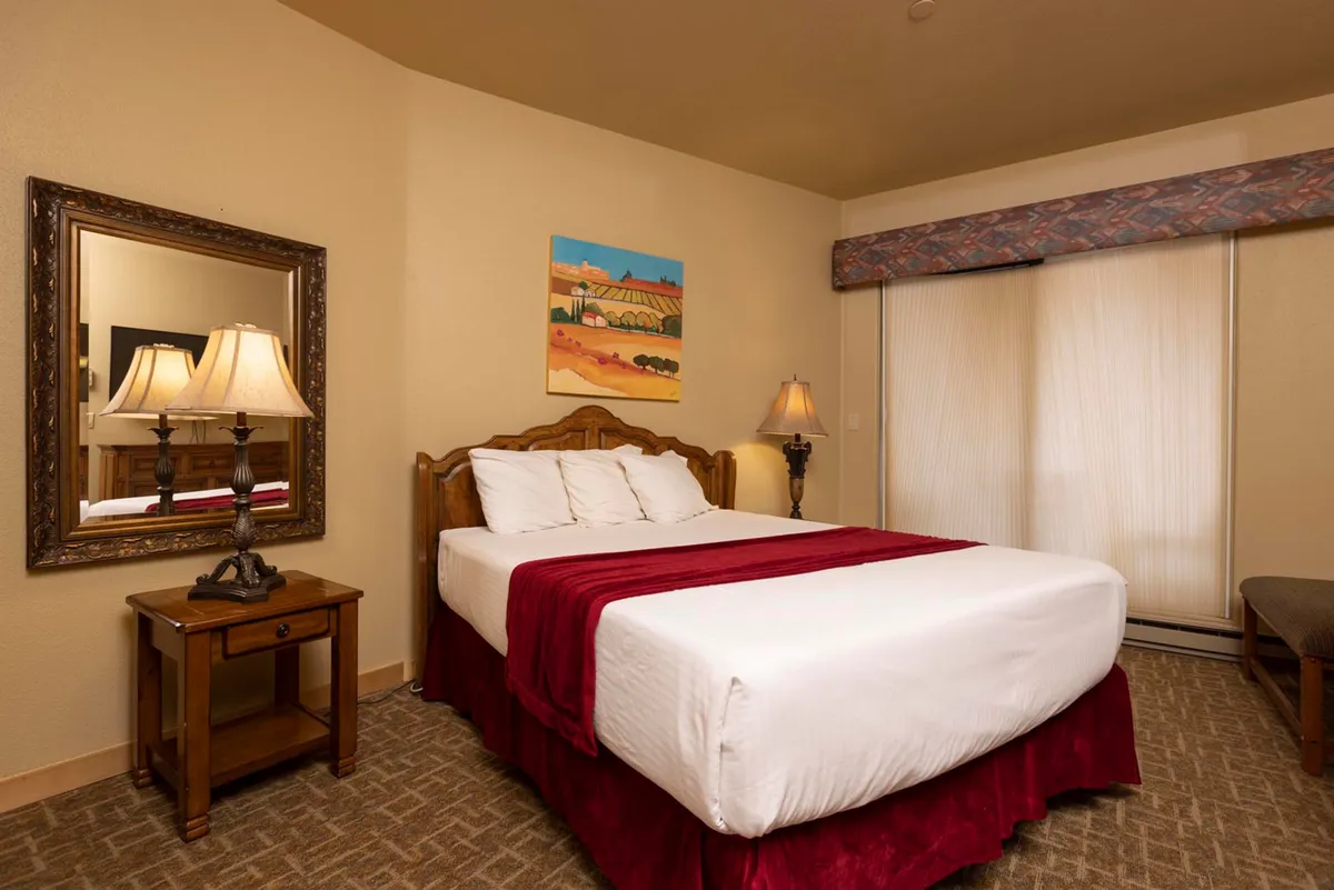 A cozy bedroom with a comfortable bed, a stylish mirror reflecting soft light, a table lamp ideal for evening reading, and elegant wall art. Natural light streams through, creating a peaceful, inviting environment for unwinding and restful sleep.